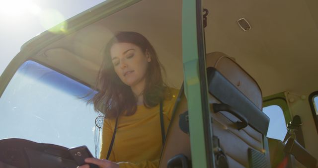 Low angle view of woman using mobile phone in the van. Beautiful woman sitting in the van 4k