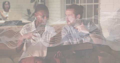 Collaborating on sofa with laptop and digital waveform overlay for remote brainstorming