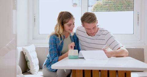 Couple Sharing Morning Coffee and Reading Together in Bright Kitchen