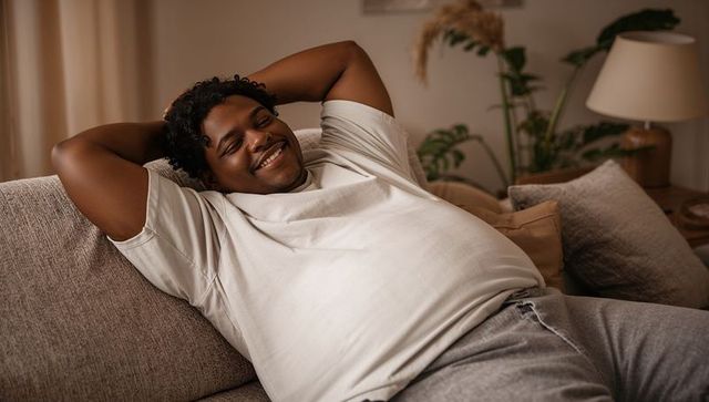 Relaxed man reclining on sofa in cozy living room smiling casual home comfort lifestyle