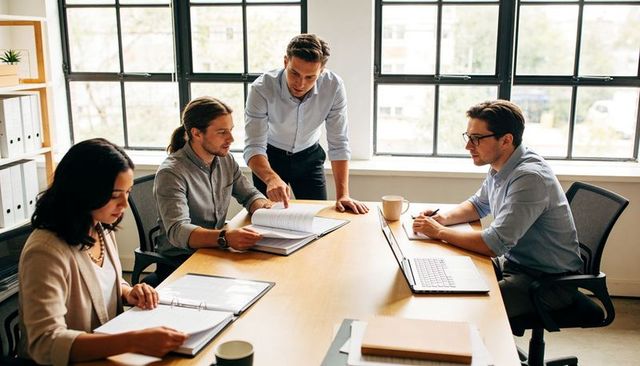 Young professional team collaborating and reviewing documents in bright modern office meeting