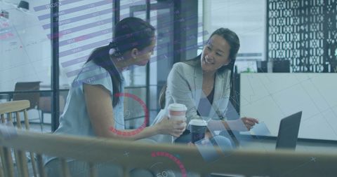 Businesswomen analyzing financial projections in modern office
