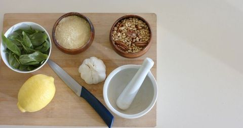 Pesto ingredients flatlay featuring basil lemon garlic pine nuts parmesan mortar