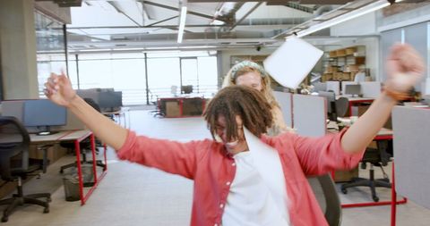 Colleagues having fun spinning on chair during office break