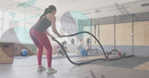 Woman cross training with battle ropes in modern gym