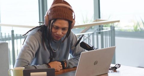 Creative podcaster recording with laptop and condenser microphone in bright workspace