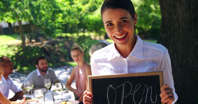 Smiling Woman Holding Open Sign at Outdoor Cafe - Download Free Stock Images Pikwizard.com