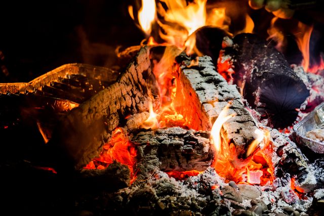 Captures warm and cozy atmosphere of a bonfire with burning logs and glowing embers. Useful for depicting camping, outdoor activities, and evenings spent by the fire. Great for illustrating warmth and relaxation, advertising outdoor adventure gear, or representing communal gatherings.