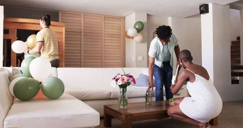 Friends Preparing Home Celebration with Balloons and Snacks