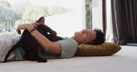Young man enjoying quality time with puppy in bright living room