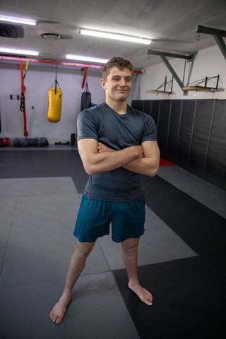 Confident barefoot boxer standing with arms crossed in martial arts gym training