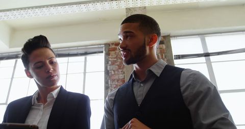 Two professionals discussing business in modern office environment