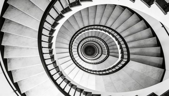 Spiraling Stone Staircase Creating Concentric Ovals with Symmetrical Metal Railing