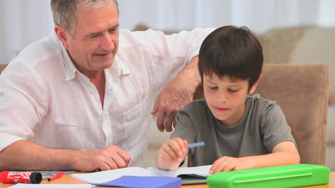 Grandfather Helping Grandson with Homework at Table