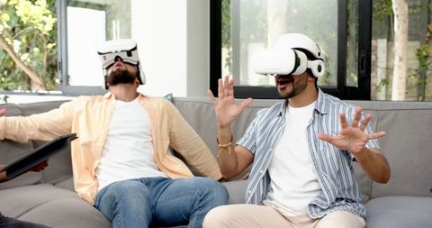 Friends experiencing virtual reality technology relaxing at home