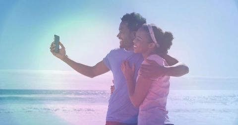 Couple hugging while taking selfie at peaceful beach shoreline