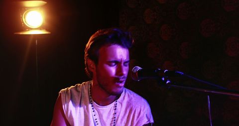 Passionate Male Musician Singing on Dimly Lit Stage - Download Free Stock Images Pikwizard.com
