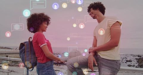 Couple enjoying seaside chatting with digital communication overlay