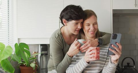 LGBTQ Couple Sharing Cozy Moment in Kitchen with Smartphone