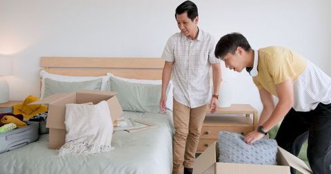 Two men packing for vacation in hotel room