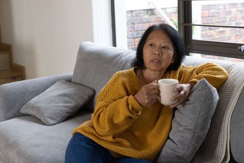 Senior Woman Relaxing with Coffee at Home in Cozy Living Room