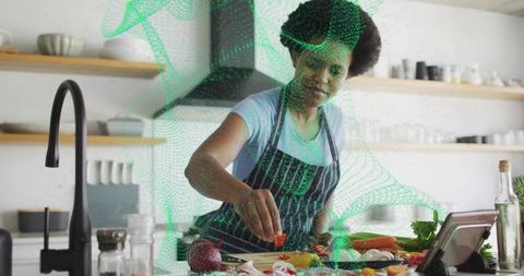 Home cook preparing fresh vegetables at bright kitchen island while following tablet recipe