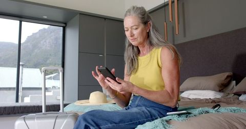 Mature Woman Relaxing on Bed with Smartphone During Travel