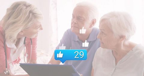 Home nurse consulting senior couple with tablet displaying 29 likes for telehealth care