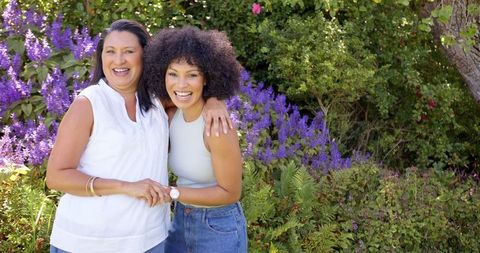 Smiling Diverse Women Embracing in Lush Garden Setting