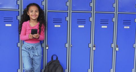 Smiling Young Girl with Smartphone Leaning on Blue School Lockers - Download Free Stock Images Pikwizard.com