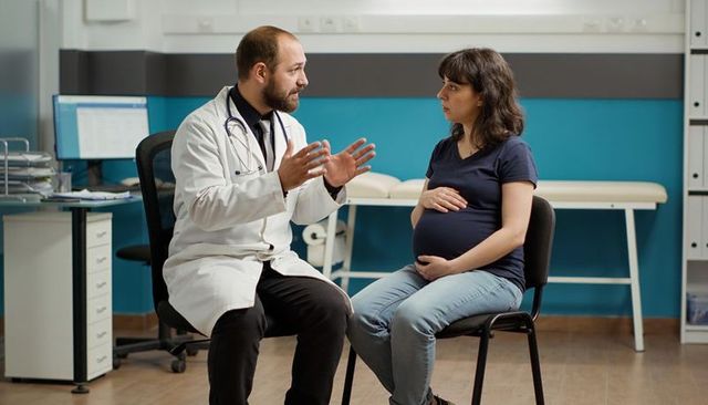 Pregnant woman consulting doctor in clinic discussing prenatal care and birth plan
