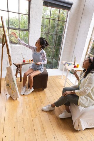 Mother and daughter painting in sleek art studio