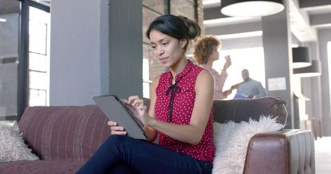 Focused Woman Using Tablet in Modern Office Lounge
