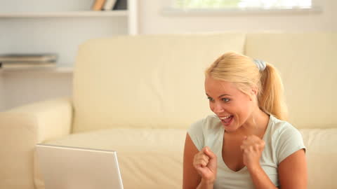 Cheerful Woman Ecstatically Using Laptop Indoors