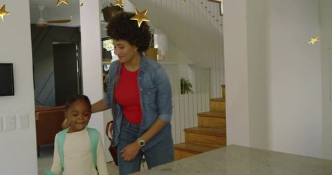 Parent guiding daughter with backpack preparing for school morning routine at home kitchen