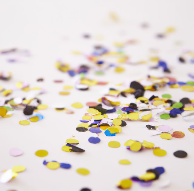 Close-up view of colorful confetti scattered on white background. Useful for party invitations, festive advertisements, celebratory banners, and joy-filled event promotions. Great for birthday, wedding, and holiday promotional materials.