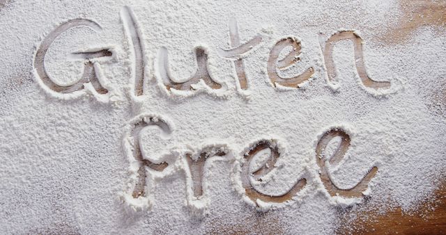 Words Gluten Free are written in flour spread out on a surface, with copy space. It signifies the importance of dietary restrictions and the growing trend of gluten-free products for health reasons.