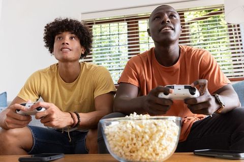 Diverse friends gaming on sofa with popcorn