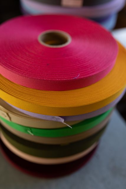 This image showcases a high angle view of colorful ribbons stacked in a hat factory workshop. Ideal for use in articles or advertisements related to textile manufacturing, crafting, sewing supplies, and creative workspaces. Perfect for illustrating the vibrant and diverse materials used in the fashion and textile industry.