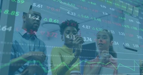 Diverse team analyzing stock charts on glass wall while collaborating in modern office