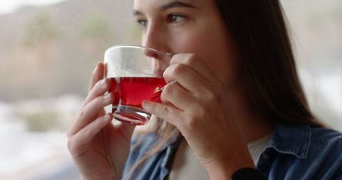 Woman drinking red tea by window on cozy winter day