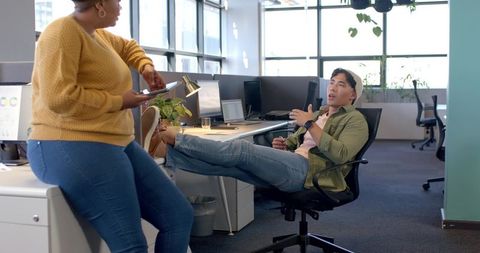 Coworkers collaborating and chatting in modern open office with casual vibe