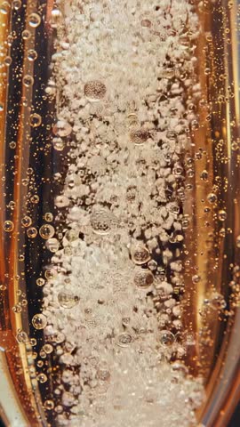 Macro Vertical Video Showing Nucleation and Rising Bubbles in Golden Sparkling Beverage