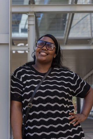 African american woman smiling and leaning against column under glass canopy