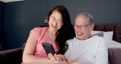 Asian Mother and Daughter Enjoying Time Together Looking at Smartphone