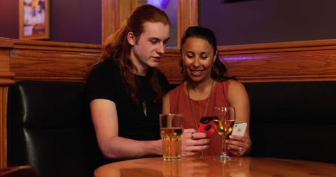 Two Women Sharing Smartphone at Bar Enjoying Connection