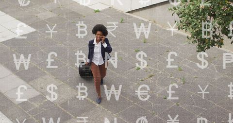Businesswoman walking with luggage and currency symbols overlay