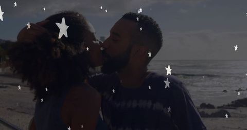 Happy couple kissing on beach with creative stars overlay