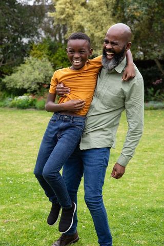 Father Lifting Son Joyfully in Backyard Garden