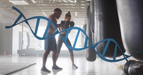 Shirtless trainer guiding female boxer with dna helix overlay representing genetic fitness